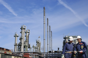 oil and gas workers with large oil refinery in background