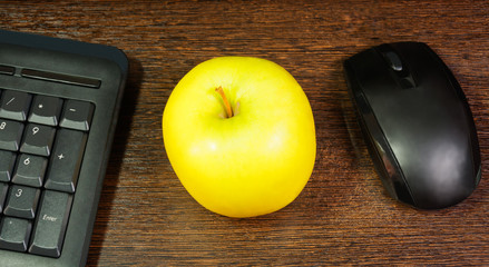 Composition with green apple,  mouse and keyboard laying on wood