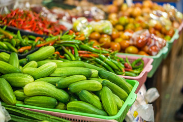 Heap of cucumbers (Cucumis sativus) in plastic basket for sale