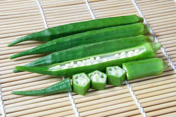 Fresh green okra with bamboo mat background