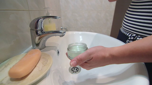 Woman applying facial cream in the bathroom close-up