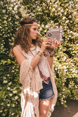 boho young woman among flowers playing with retro camera © Alliance