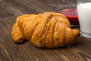 Breakfast with croissants, milk and strawberry jam.