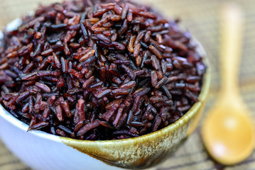 Close up rice berry in bowl with wooden spoon.