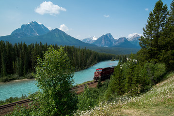A train going thru a beautiful mountain in Canada