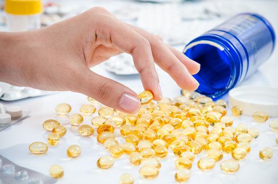 Woman’s Hand Holding A Fish Oil Pill 
