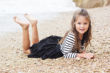 Child girl is wearing stripped dress on the beach