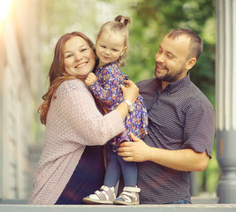 Fototapeta premium Mom and young daughter and dad, a young family on a walk in the park in summer