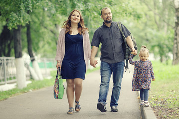 Mom and young daughter and dad, a young family on a walk in the park in summer