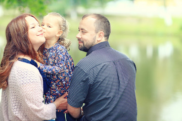 Obraz premium Mom and young daughter and dad, a young family on a walk in the park in summer