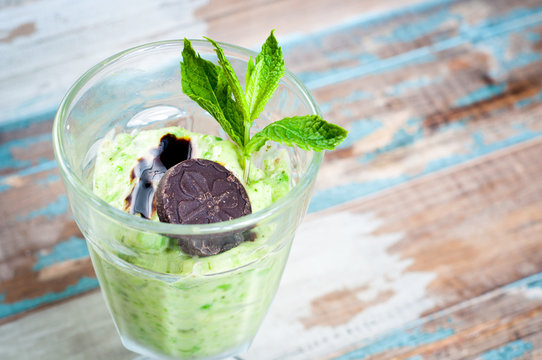 Healthy vegetable smoothie milkshake made from blended, iced yoghurt, mint and peas. Topped with some chocolate and fresh mint.