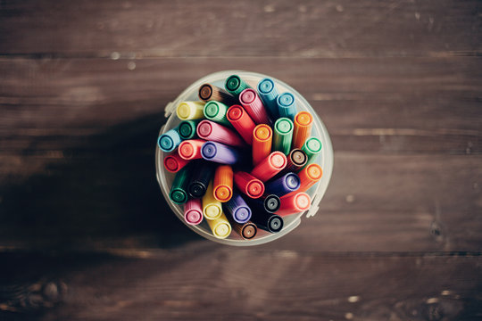 Top view, colorful felt pens on dark wooden table. Toned photo, shallow depth of field.