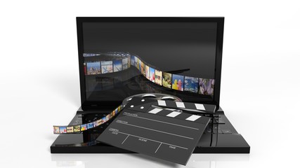 Clapperboard and film reel on black laptops keyboard isolated on white