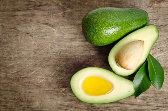 fresh avocado and  avocado like a bowl for oil on wooden backgro