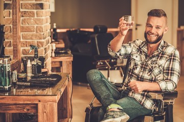 Happy client in barber shop will glass of whiskey