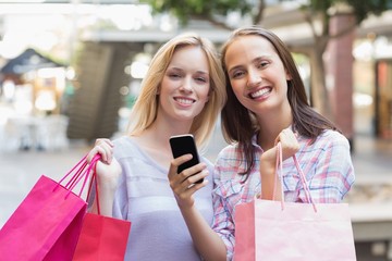 Happy women friends smiling at camera with shopping bags