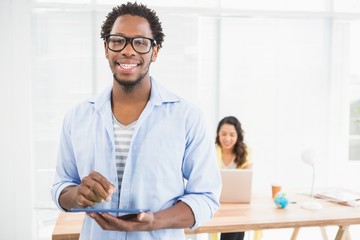 Smiling man posing in front of his colleague with tablet