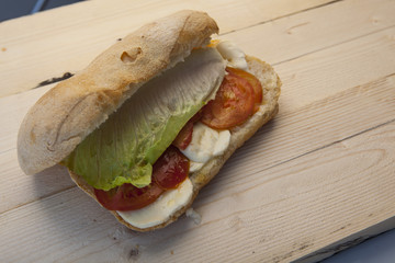 Panino con insalata mozzarella e pomodoro su piano di legno