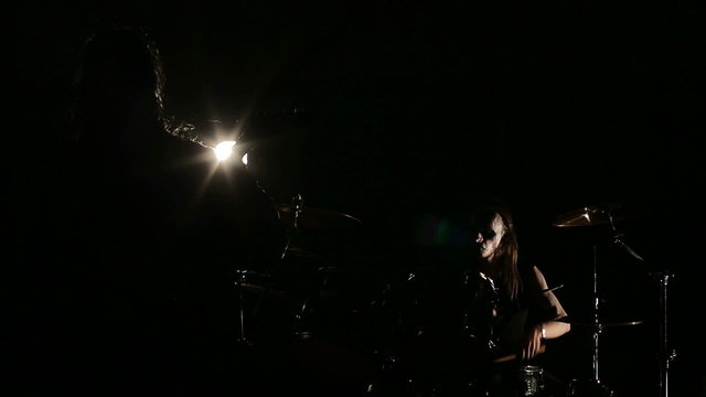 Vocalist and dreummer of black metal band at dark background