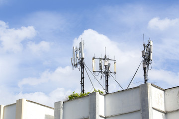 Fototapeta na wymiar Cell Phone Towers on Resident Building Roof with Blue Sky