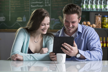 A young couple using a tablet/ipad in a cafe