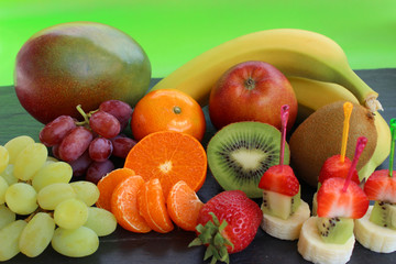 Leckere Obstspieße mit verschiedenen Obstsorten auf Schieferplatte