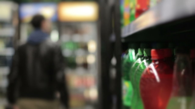 Man in a supermarket buying bottle carbonated water. Defocus background