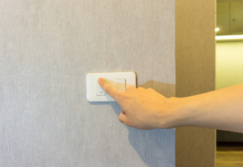 Man hand turning light on a wall switch