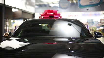 Gift expensive black car with red symbolic ribbon on a roof