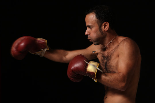 Profile of a boxer with boxing gloves, throwing a punch without shirt