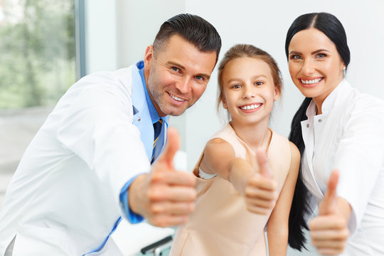 Dentist doctor,  assistant and little girl all smiling at camera