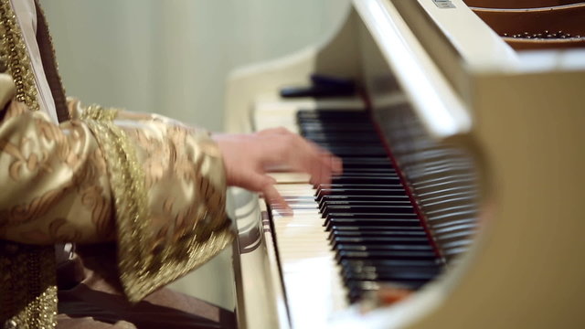 Man in a suit of the king plays a piano