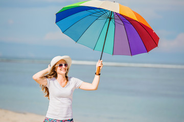 Cheerful young girl with rainbow umbrella having fun on the