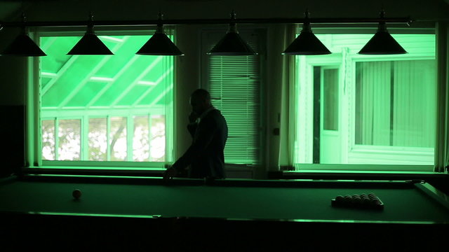Man talking on the phone in the dark billiard room