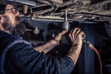 Mature mechanic at repair service station unwound screw