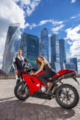 Obraz na płótnie Canvas Young couple on a sports bike on the background of the city skyl
