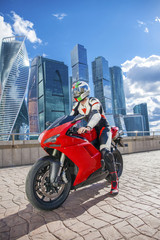 Fototapeta na wymiar Young man sits on a sports bike on the background of the city sk