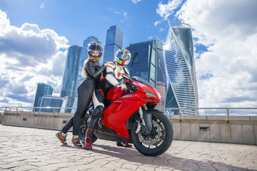 Fototapeta na wymiar Young couple on a sports bike on the background of the city skyl