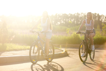 Two young women on bicycle ride in sunlight