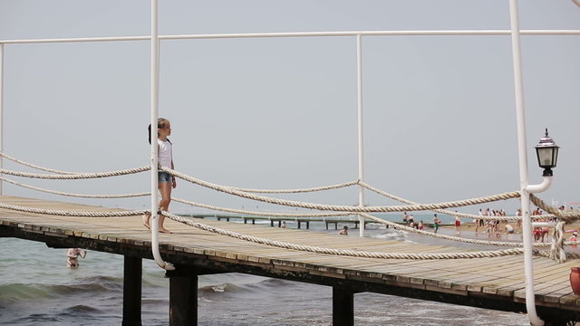 Child walking on a wooden pier near the sea