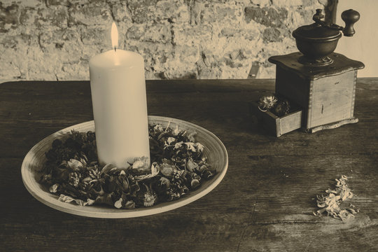 Candle on the wooden plate with coffee mill