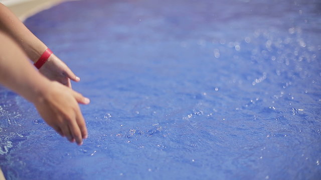 Hands of child splashing water in the pool