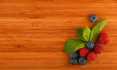 Cutting board with blueberries, raspberries and mint leaves