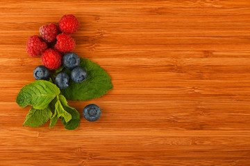Cutting board with blueberries, raspberries and mint leaves