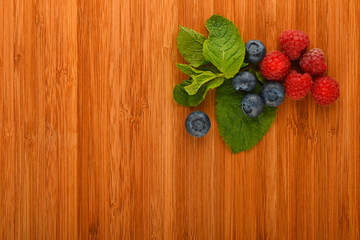 Cutting board with blueberries, raspberries and mint leaves