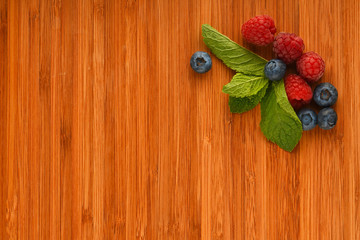 Cutting board with blueberries, raspberries and mint leaves
