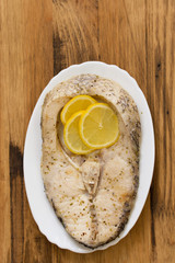 fried fish with lemon on dish on brown background