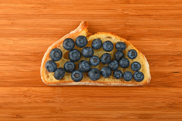 Cutting board with sandwich of blueberries on slice of bread