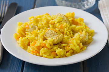 rice with meat and carrot on plate and glass of water