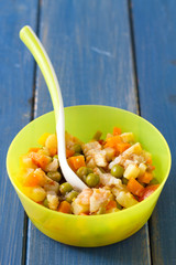 baby food in bowl with spoon on blue background